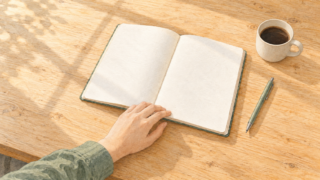 読み手の感情を決めつけず、描かれている内容を中心にまとめました。 代替テキスト 木の机に開いたノートと、ページに添えた手。そばにペンとコーヒーカップが置かれているイラスト。